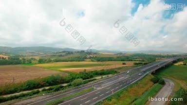 黄绿草地之间的高速公路上行驶的车辆鸟瞰图田野和农村居民点鸟瞰图